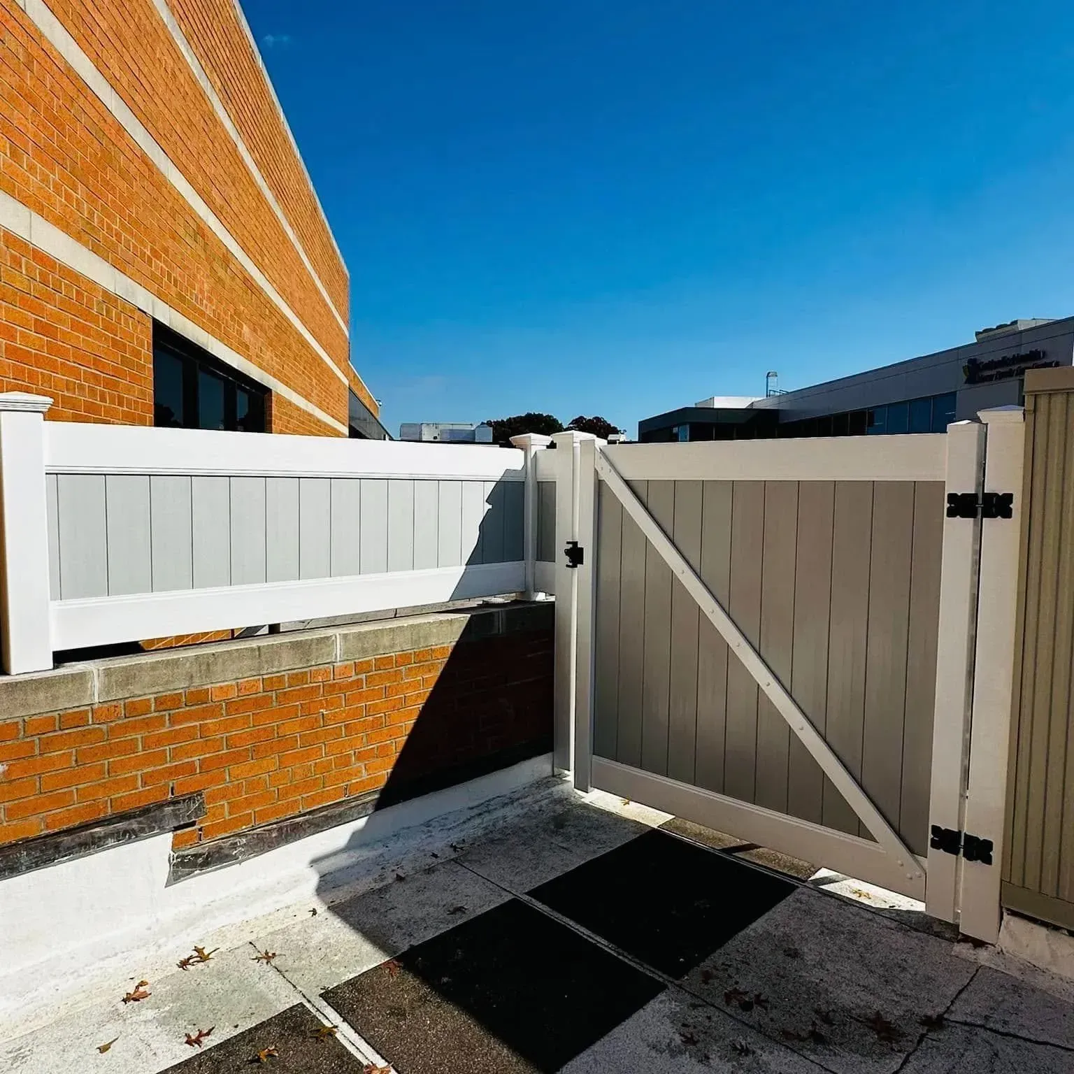 White and gray fence gate on a brick wall, with a blue sky background.