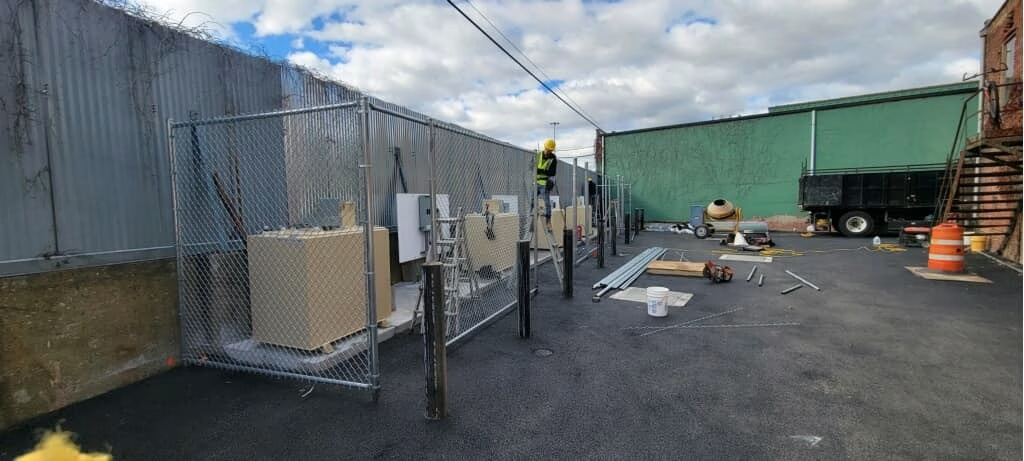 Construction site with metal fences, green building, and a dump truck.