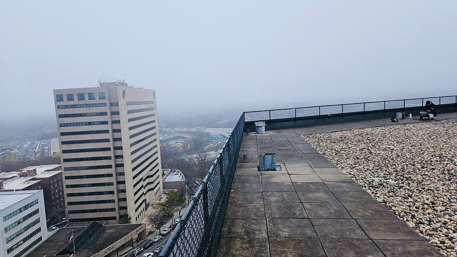 Rooftop view of a city on a foggy day. A tall building stands on the left.