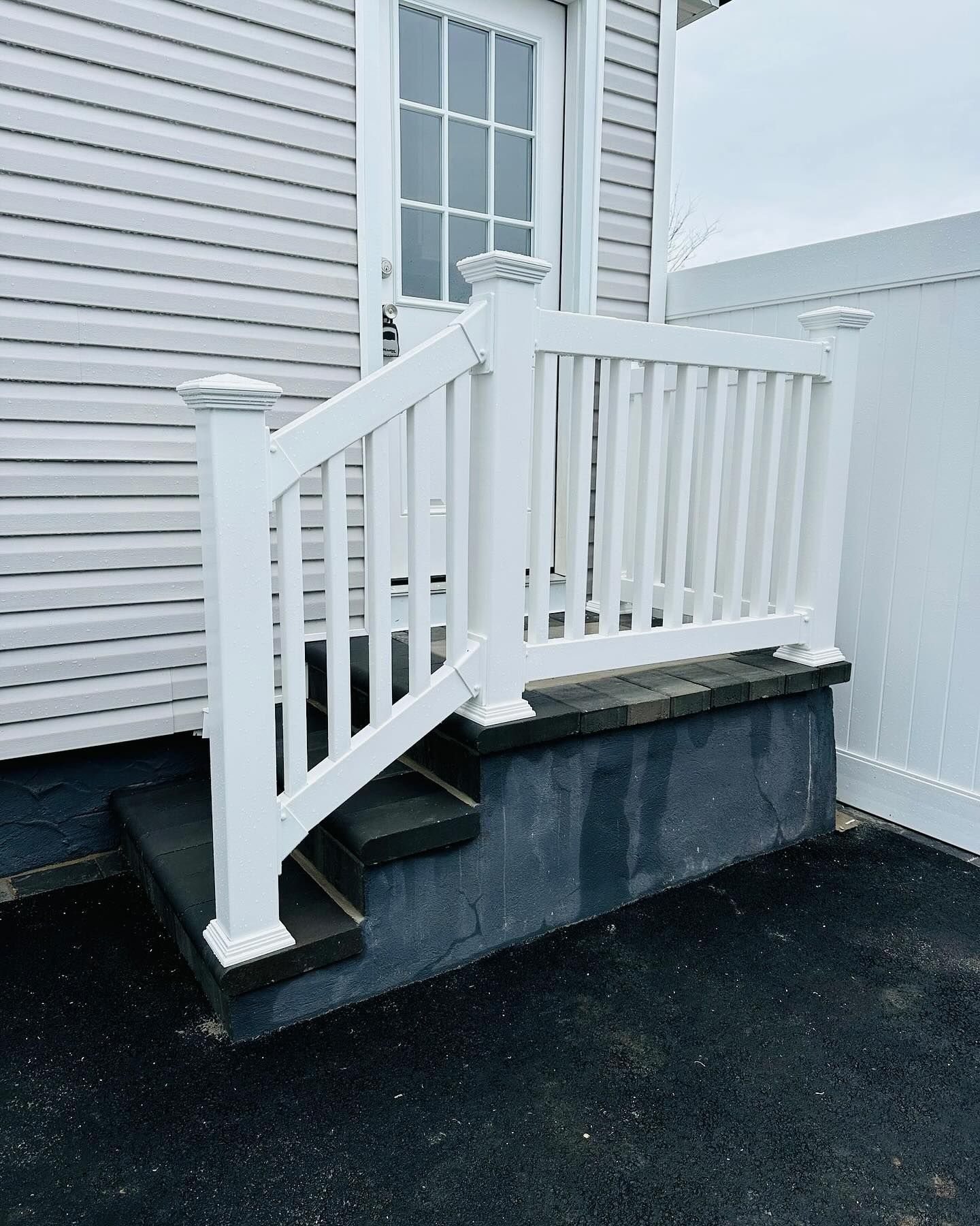 White railing and steps leading up to a door on a building with white siding.
