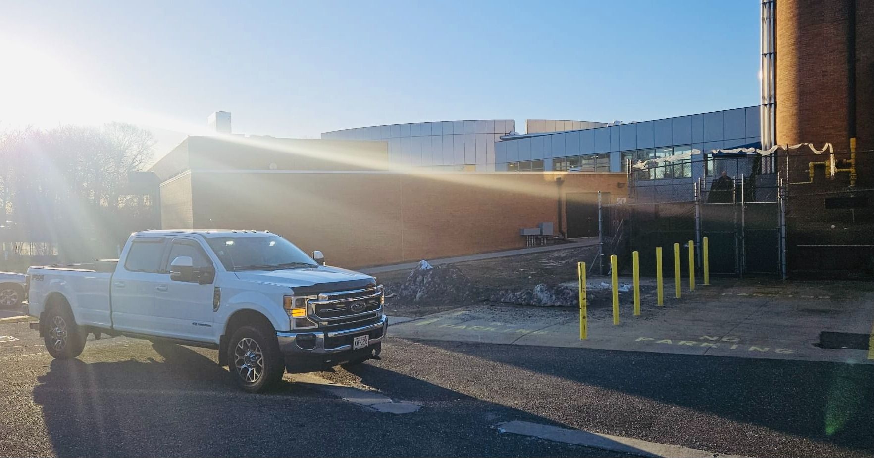 White pickup truck parked near a brick building on a sunny day.
