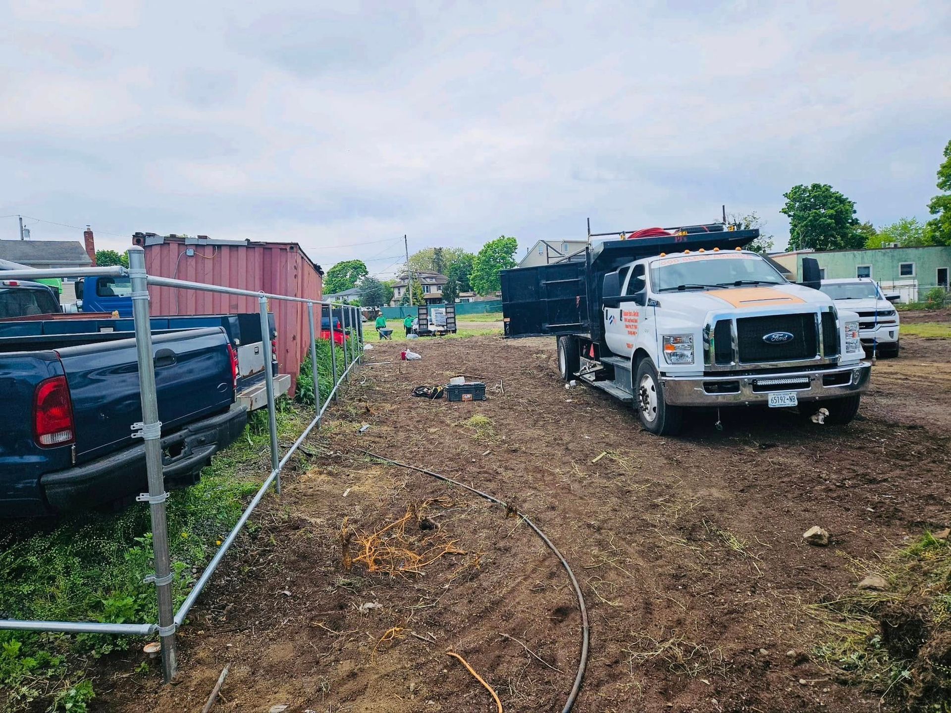 Construction site with trucks, a container, and dirt. Cloudy sky.