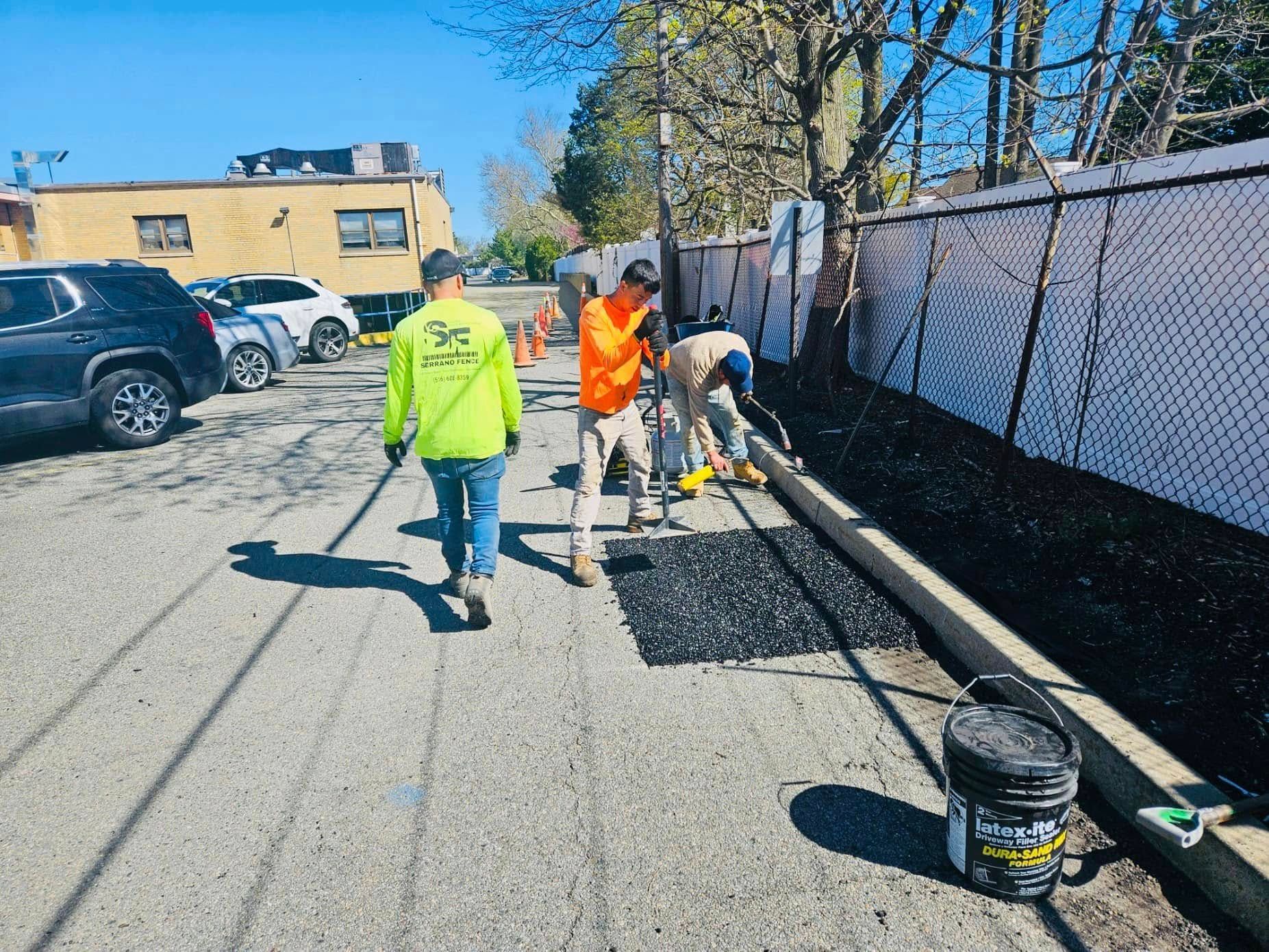 Workers in safety vests paving a parking lot.