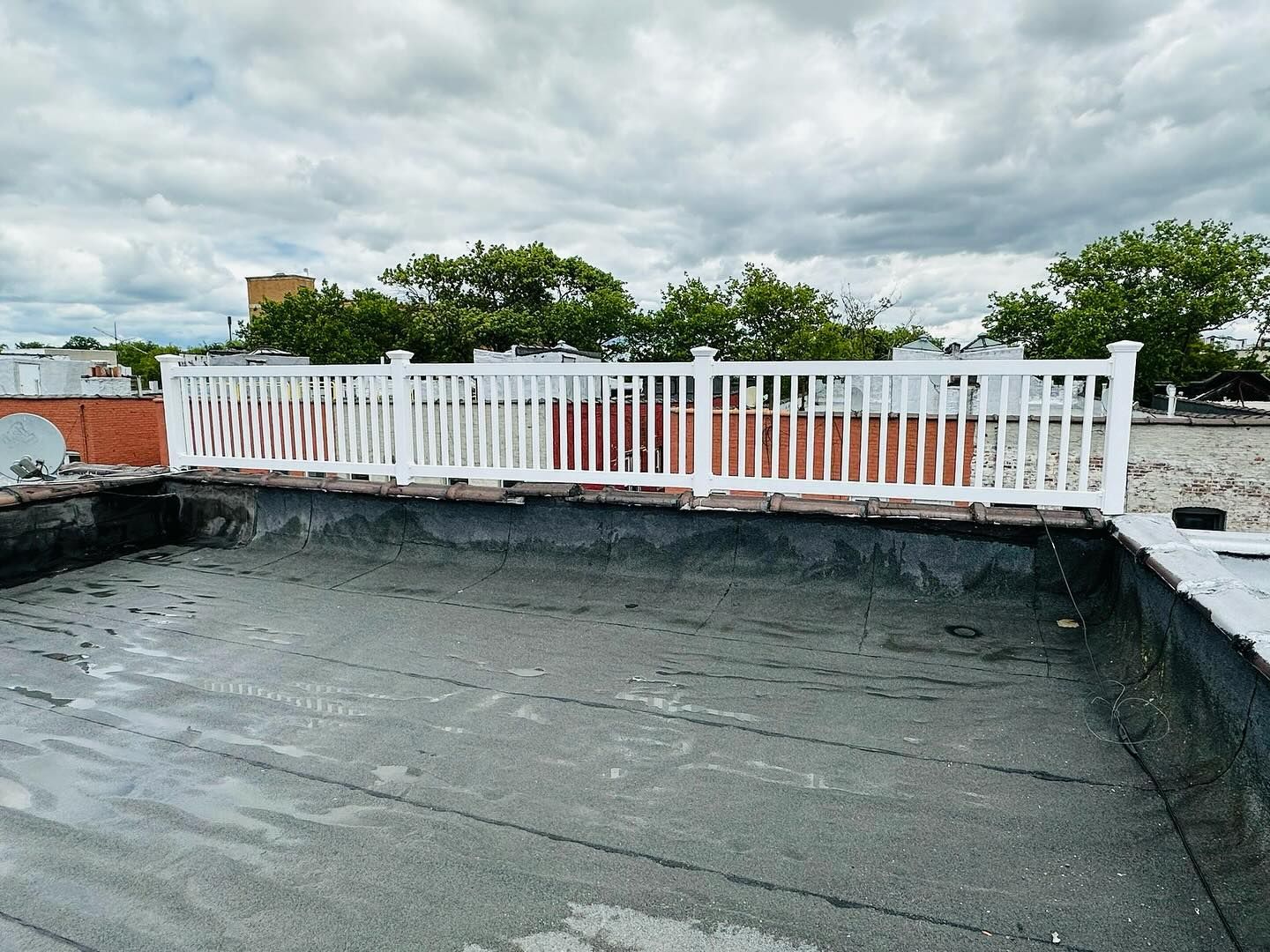 White railing on a rooftop, overcast sky. Cement and brick construction.