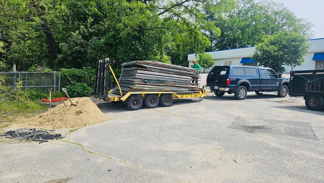 Truck towing trailer loaded with tires parked next to a sand pile.