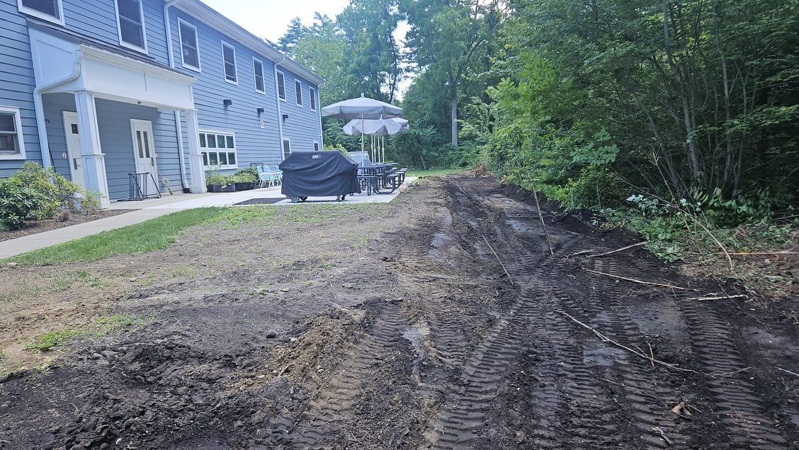 Dirt path next to a building and trees; soil looks freshly turned over.
