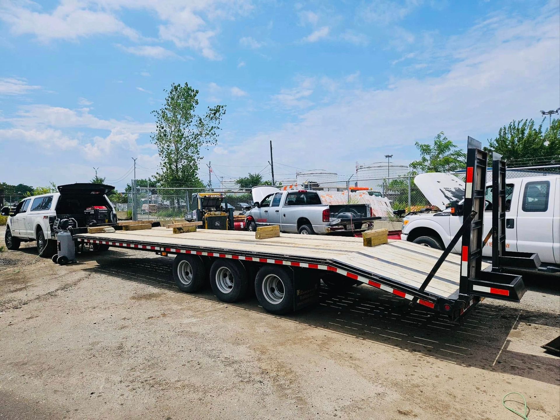 A large flatbed trailer with a truck attached, parked outside on a sunny day.