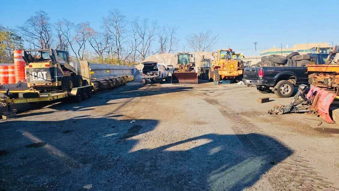 Construction equipment parked on a gravel lot under a bright blue sky.