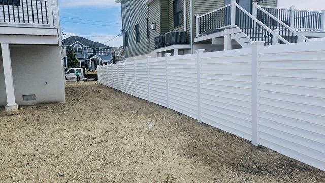 White privacy fence beside sandy yard between beach houses
