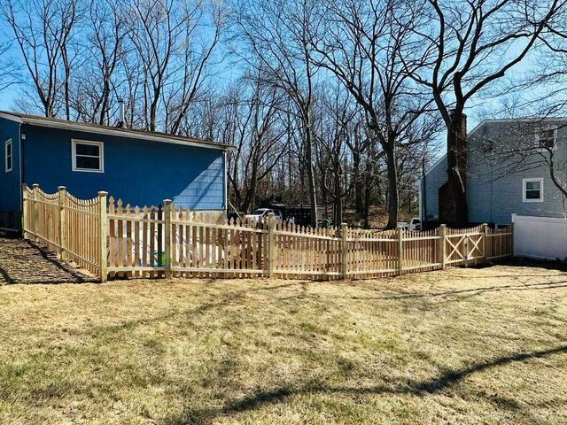 Blue house with fenced backyard and bare trees in winter sunlight