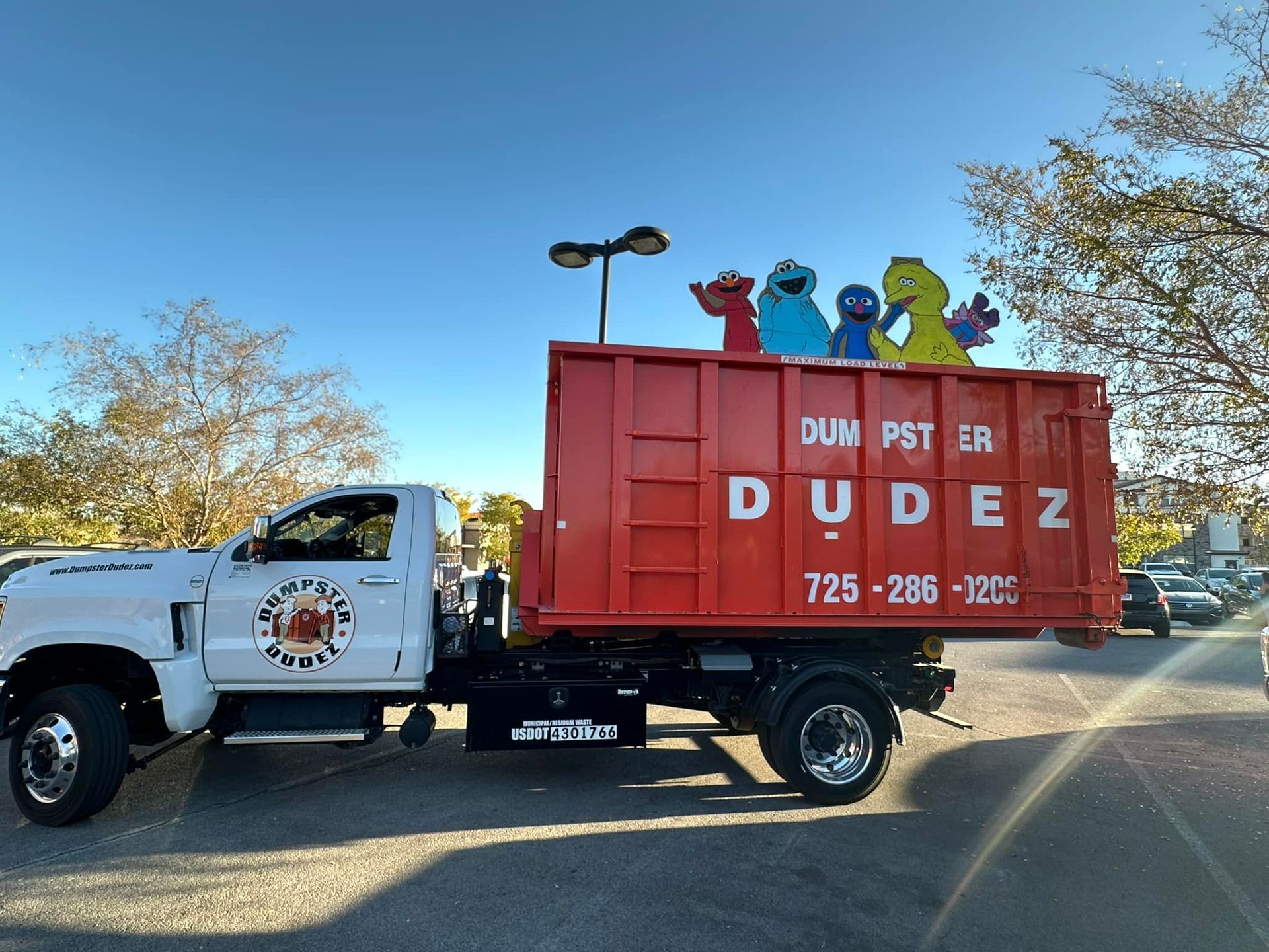 White pickup truck pulling a red DUMP POST DUDE trailer on a sunny road