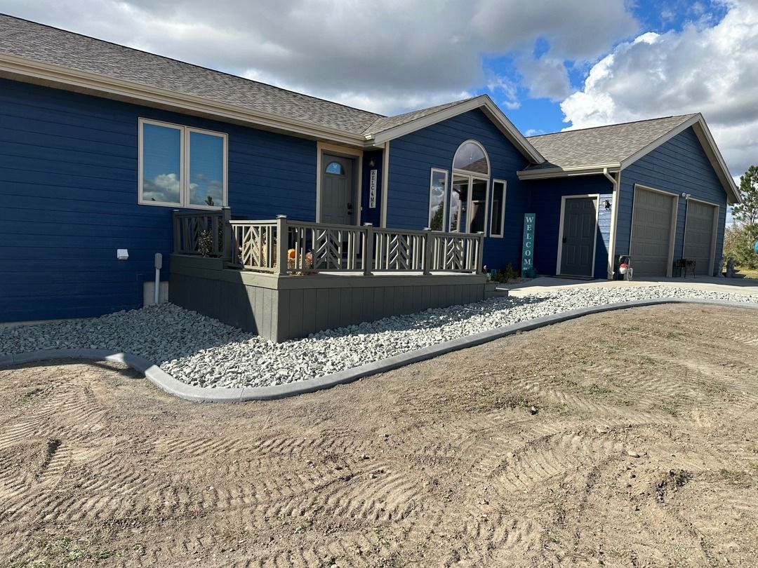 Blue house exterior with patio, gravel landscaping, and cloudy sky