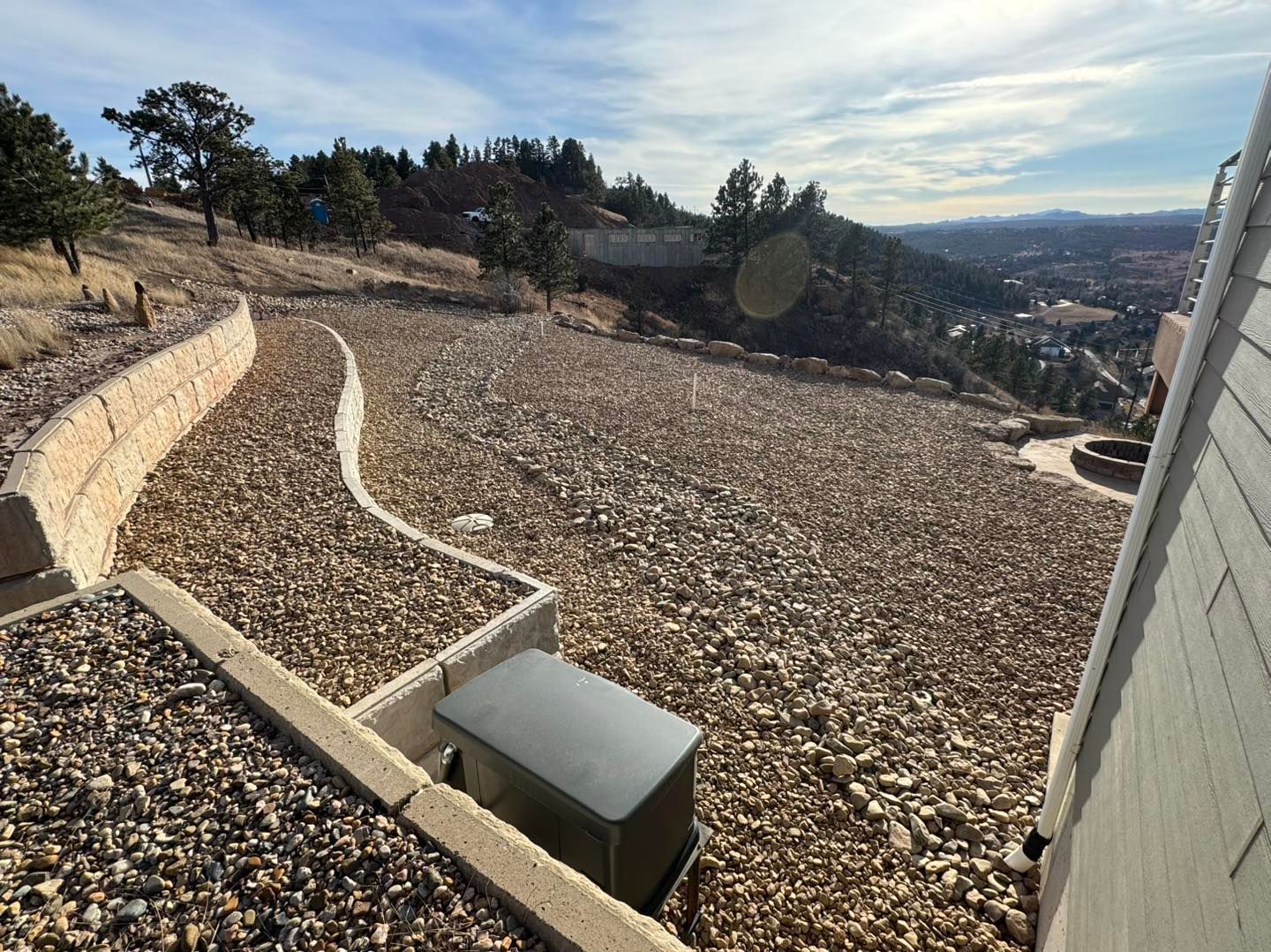 Stone steps and a winding path over a gravel hillside with a view of the valley and sky.