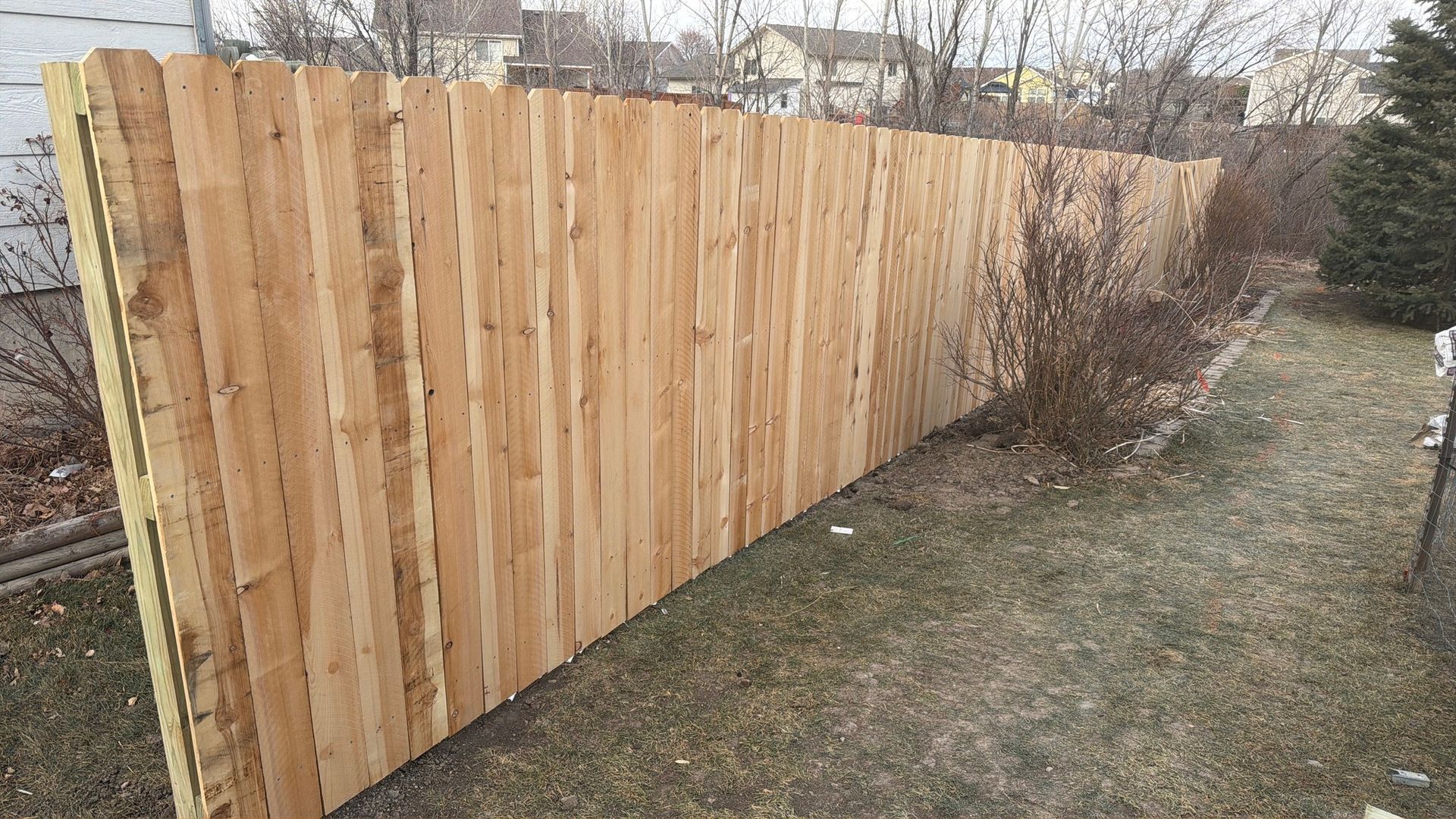 New wooden privacy fence along a grassy backyard edge