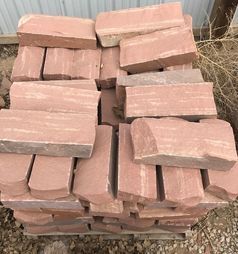 A pile of red bricks stacked on top of each other on a wooden pallet.
