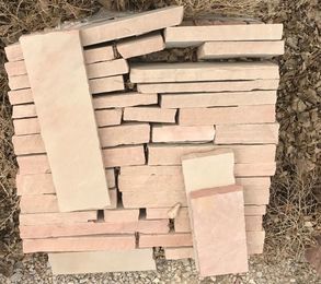 A pile of bricks stacked on top of each other on the ground.