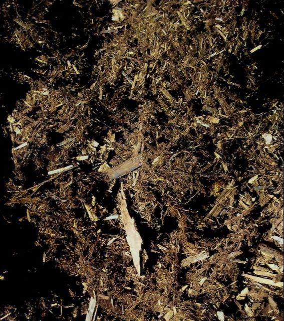 A pile of brown mulch with a piece of wood in the middle