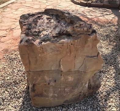 A large rock is sitting on a gravel path