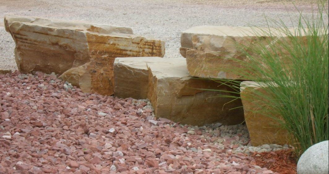 A pile of rocks sitting on top of a pile of gravel in a garden.