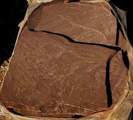 A large piece of brown rock is sitting on top of a pile of rocks.