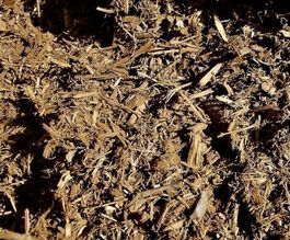 A pile of brown mulch is sitting on the ground.