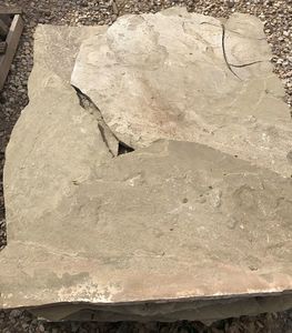 A large piece of rock is sitting on top of a pile of gravel.