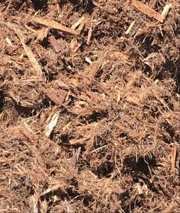 A pile of brown mulch is sitting on the ground.