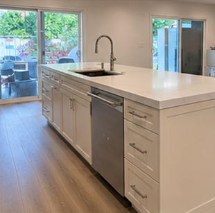 Modern kitchen with white island, stainless sink and dishwasher, and sliding doors to patio