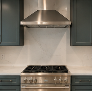 Modern kitchen with stainless steel range, hood, and dark cabinets against a light marble backsplash