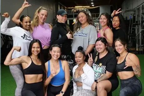A group of women are posing for a picture in a gym.