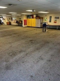A large room with a carpeted floor and a vacuum cleaner in it.