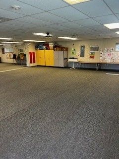 A large empty room with a carpeted floor and a table.