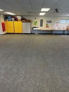 A large room with a carpeted floor and a lot of cabinets and tables.