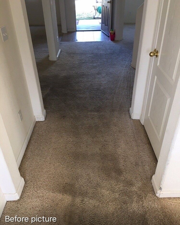 A hallway with a carpeted floor and white doors leading to a doorway.