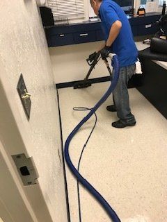 A man is cleaning the floor with a vacuum cleaner.