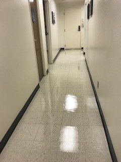 A long hallway with white tile floors and white walls.