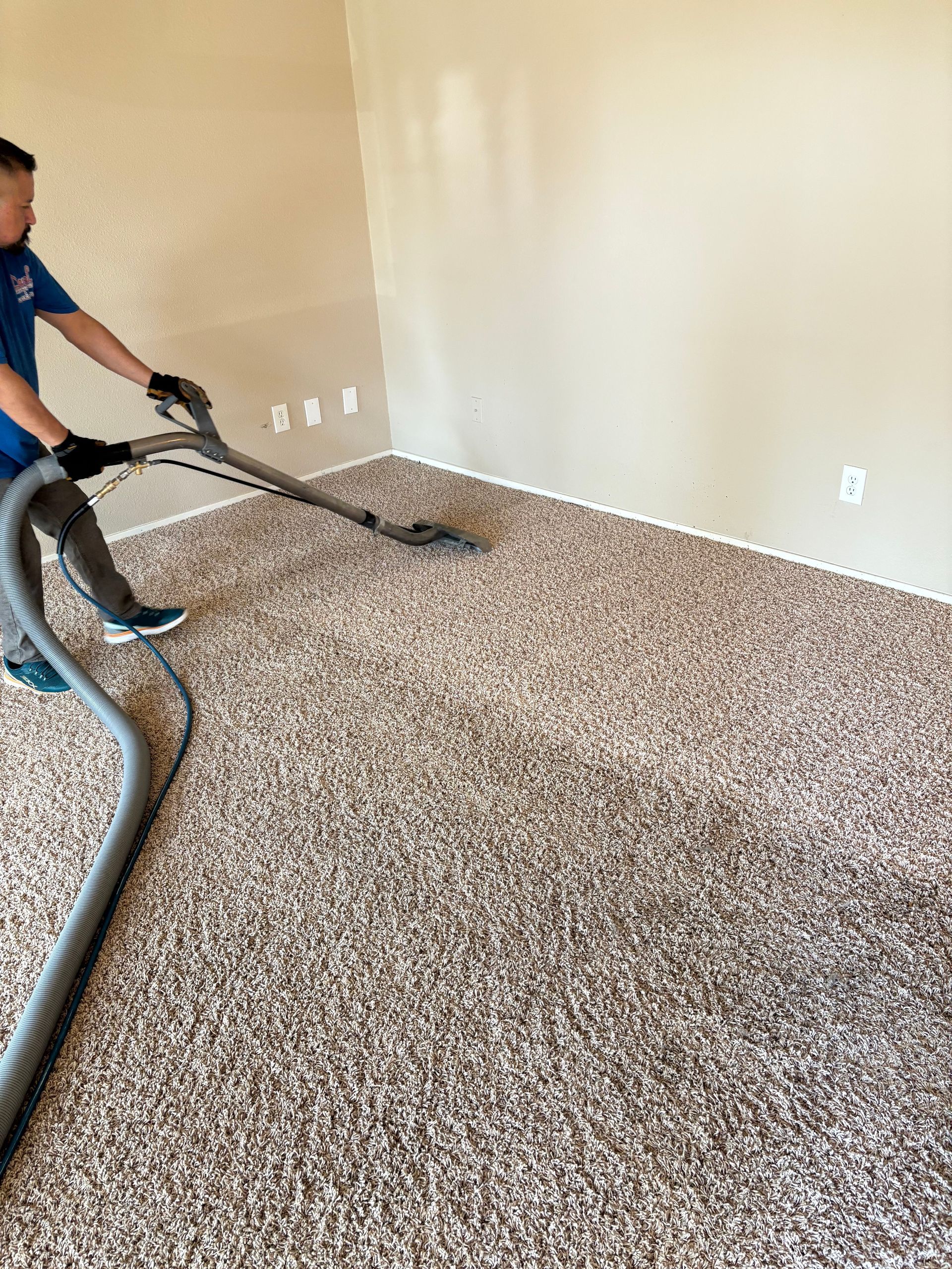 A man is using a vacuum cleaner to clean a carpet in a living room.