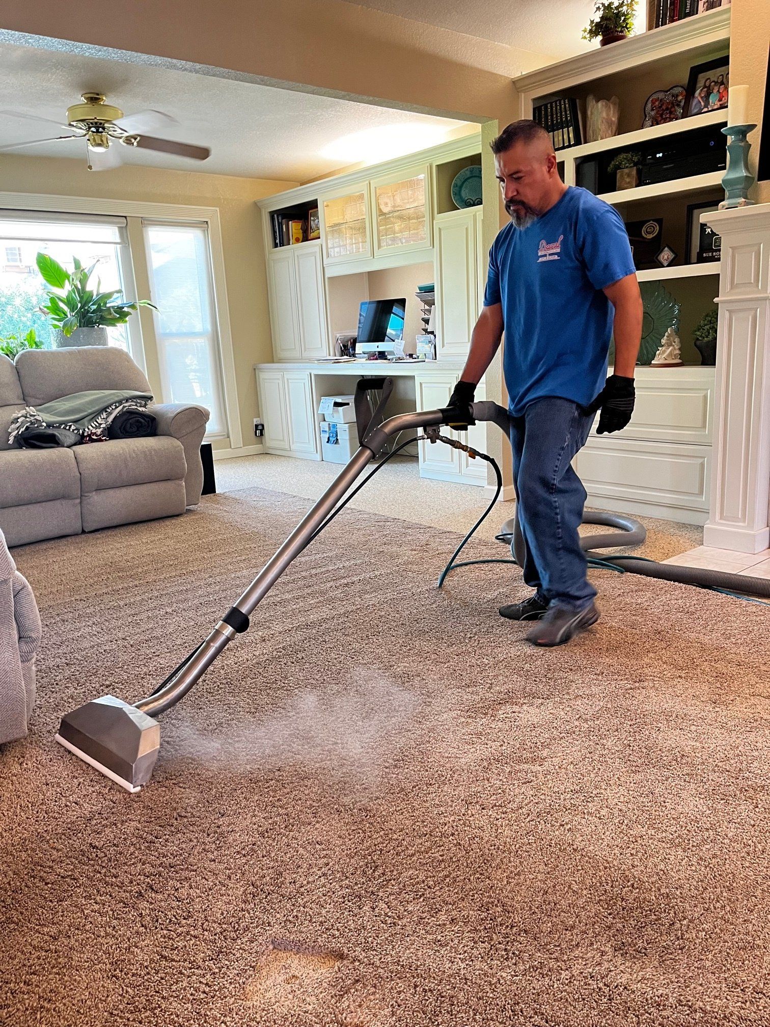 A man is using a vacuum cleaner to clean a carpet in a living room.
