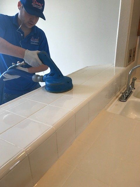 man using equipment to clean kitchen counter grout
