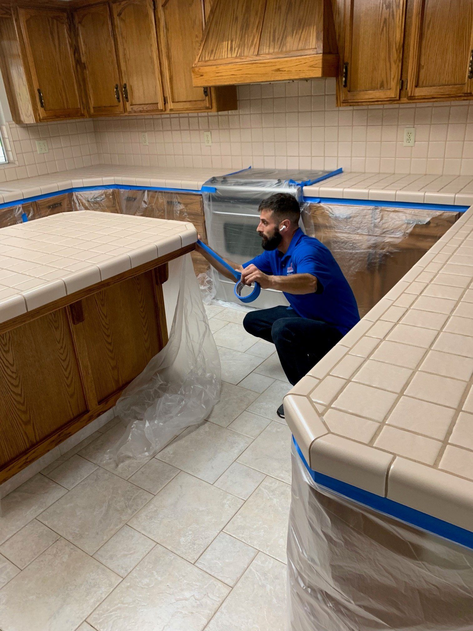 man covering the kitchen cabinets with plastic and blue tape