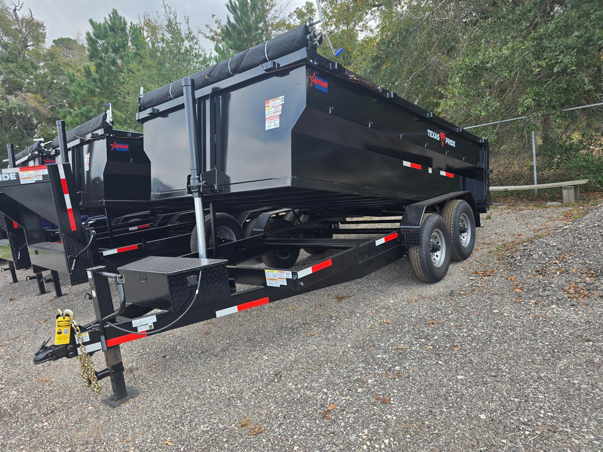 Black dump trailer parked on gravel.