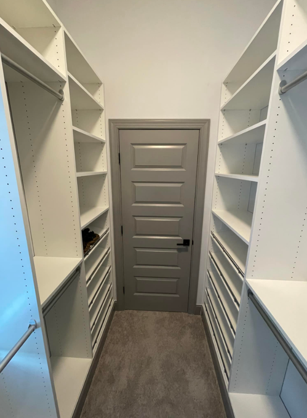a walk in closet with lots of shelves and a door