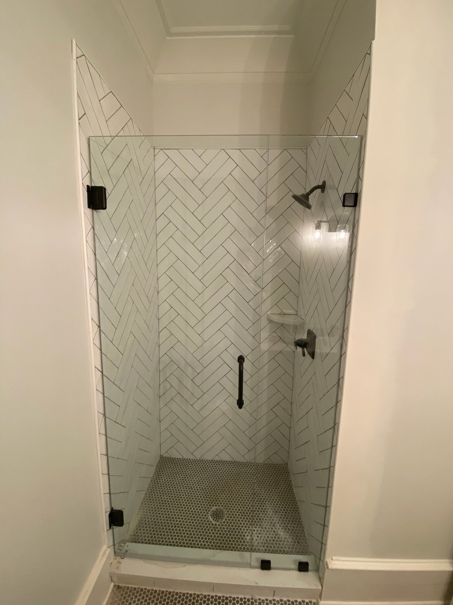 a shower stall with a herringbone pattern on the wall