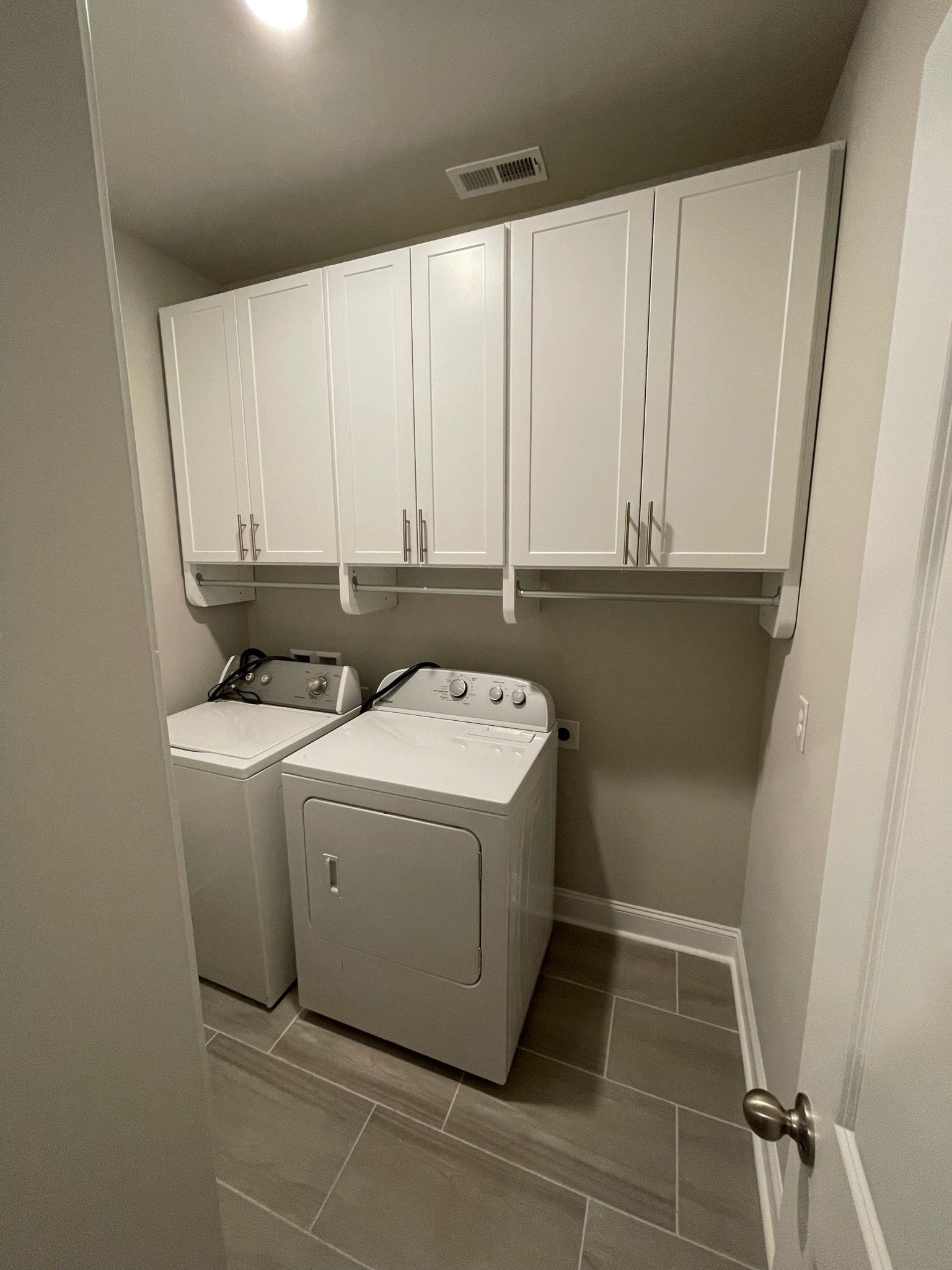 a laundry room with a washer and dryer and white cabinets