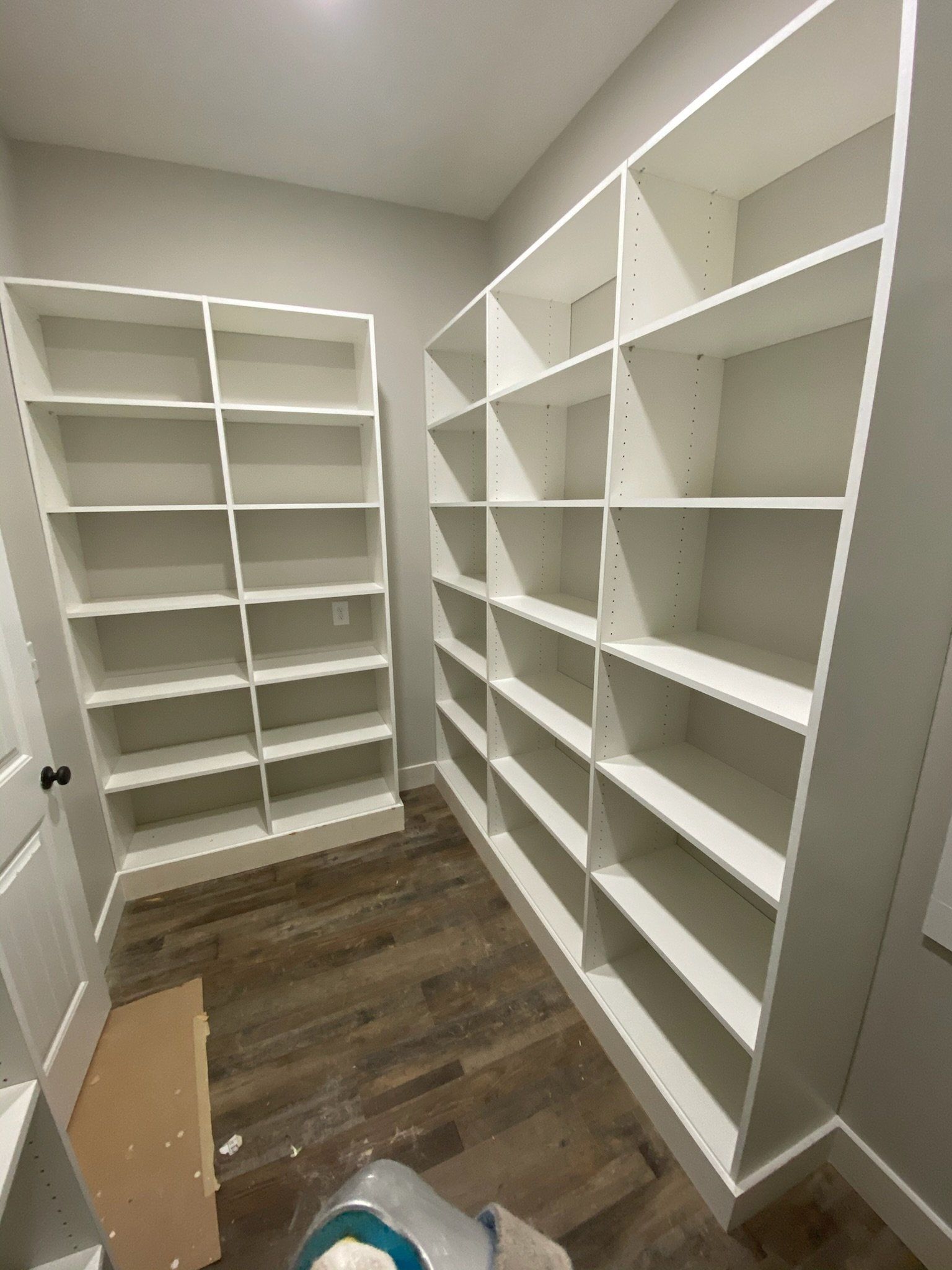 a walk in closet with lots of shelves and a wooden floor
