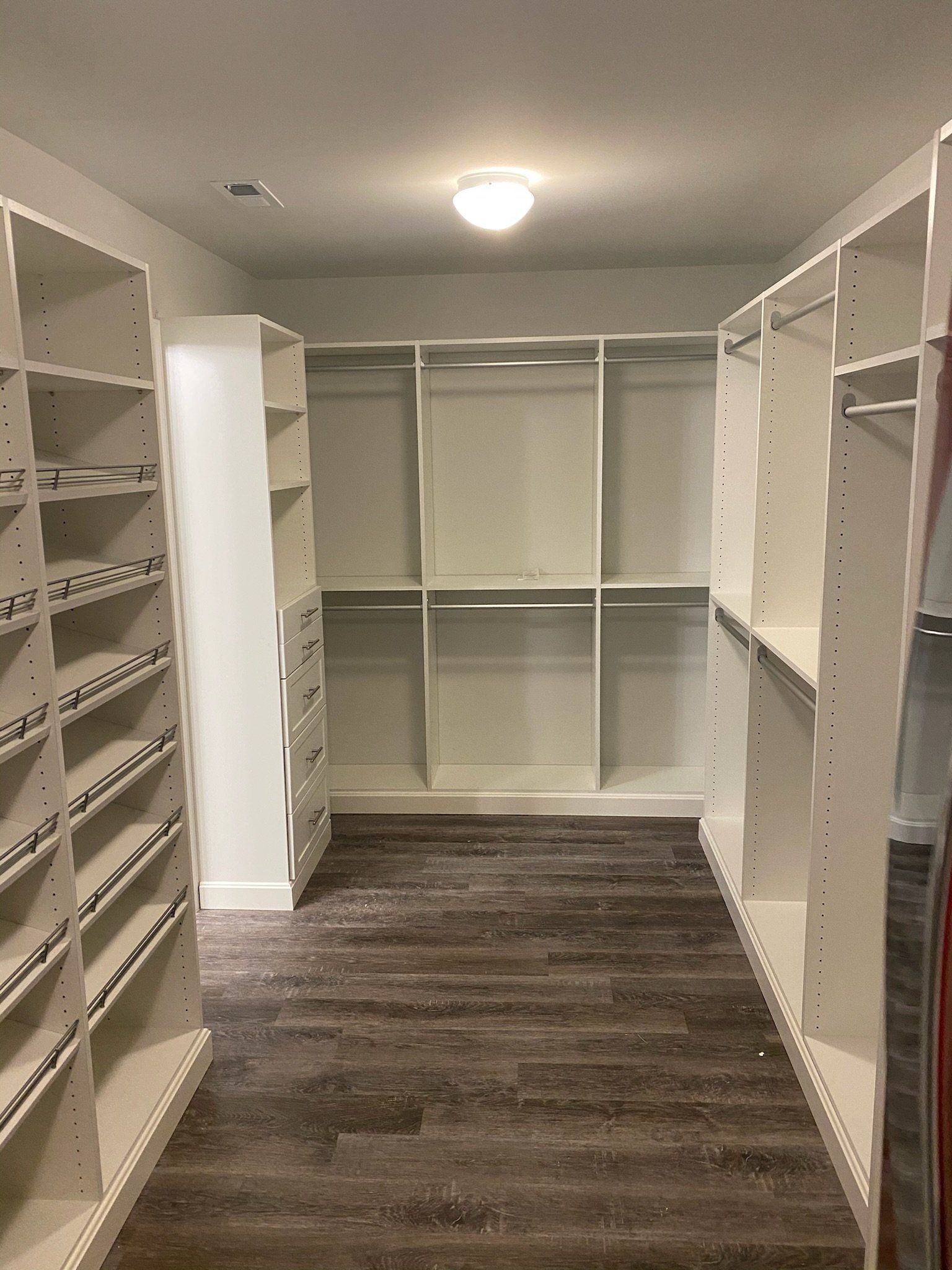 a large walk in closet with white custom cabinets