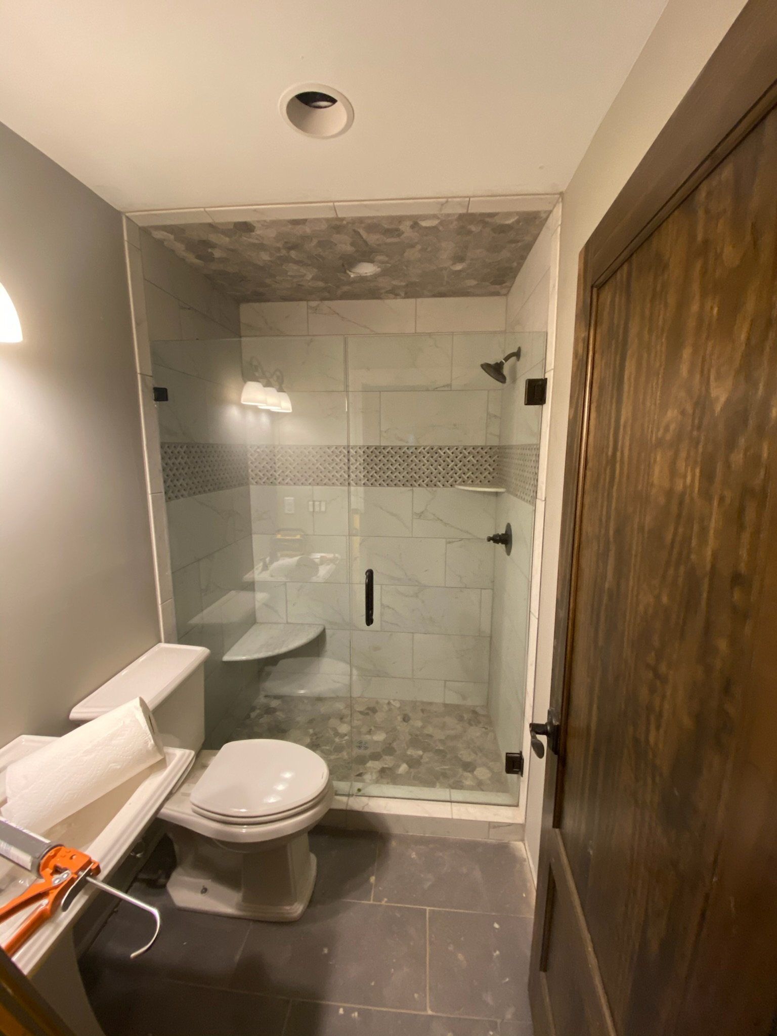a bathroom with a toilet, sink, and a shower with a frameless glass door