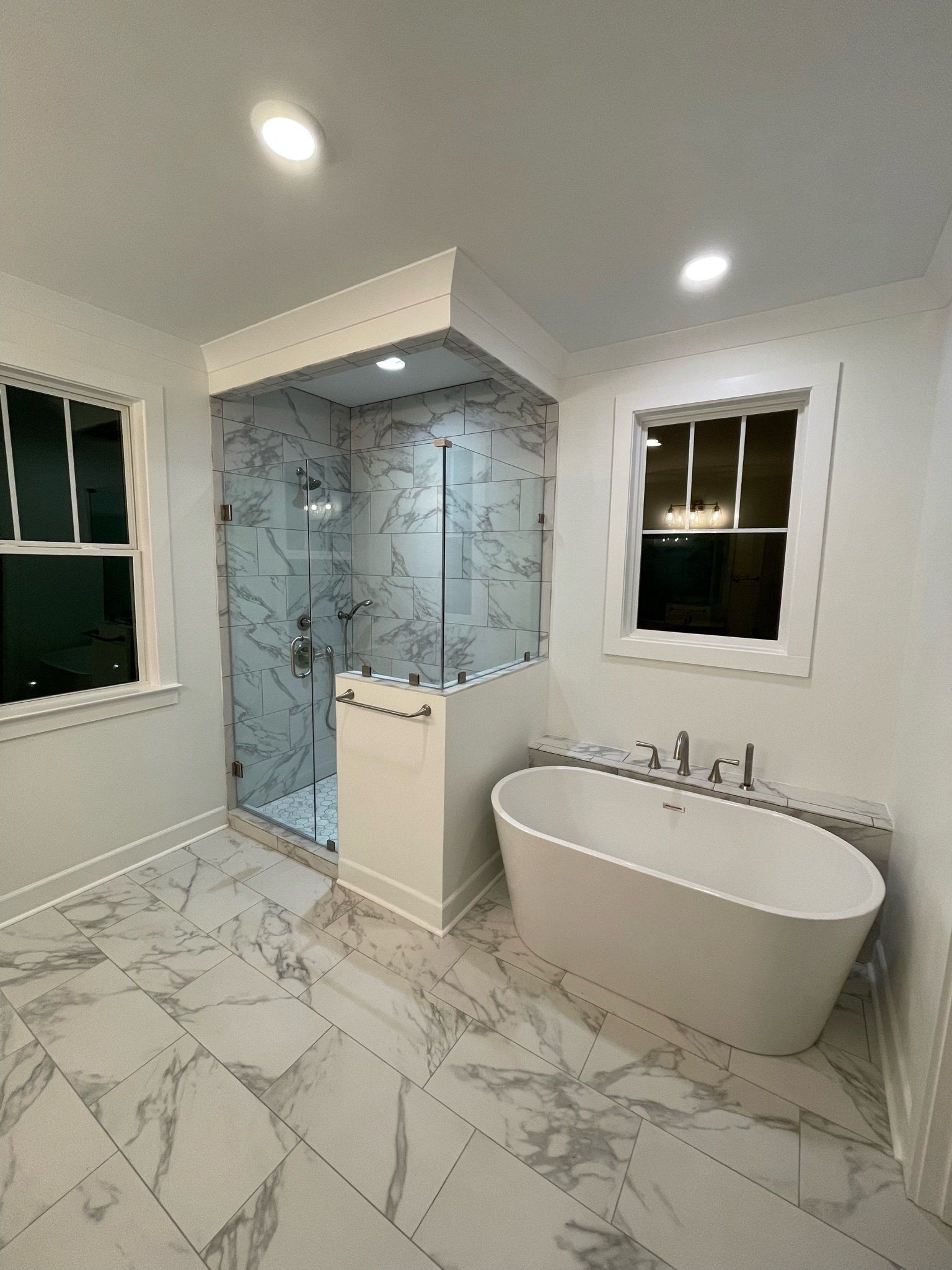 a bathroom with a tub, shower, and windows