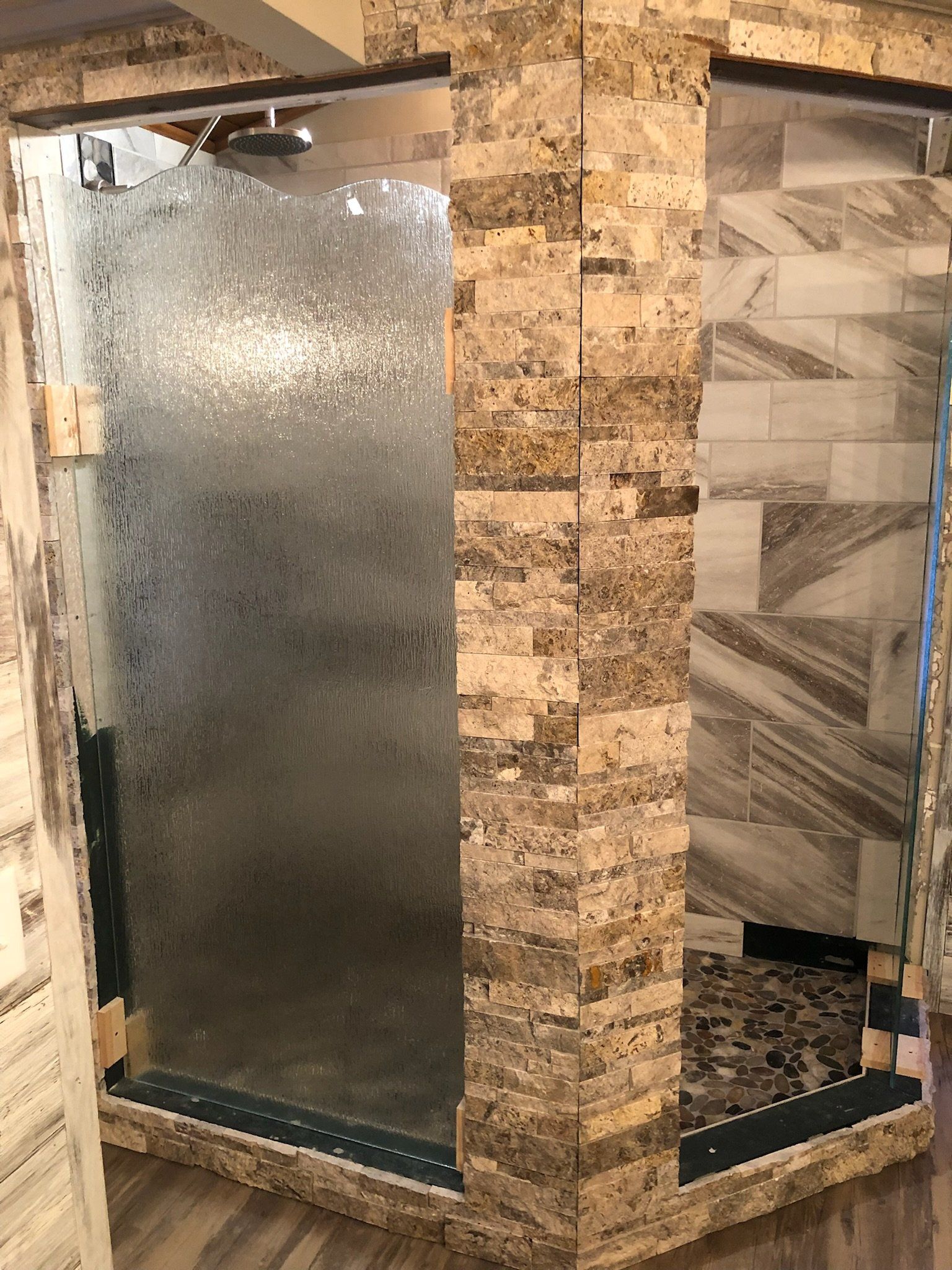 a bathroom with a walk in shower and a brick wall