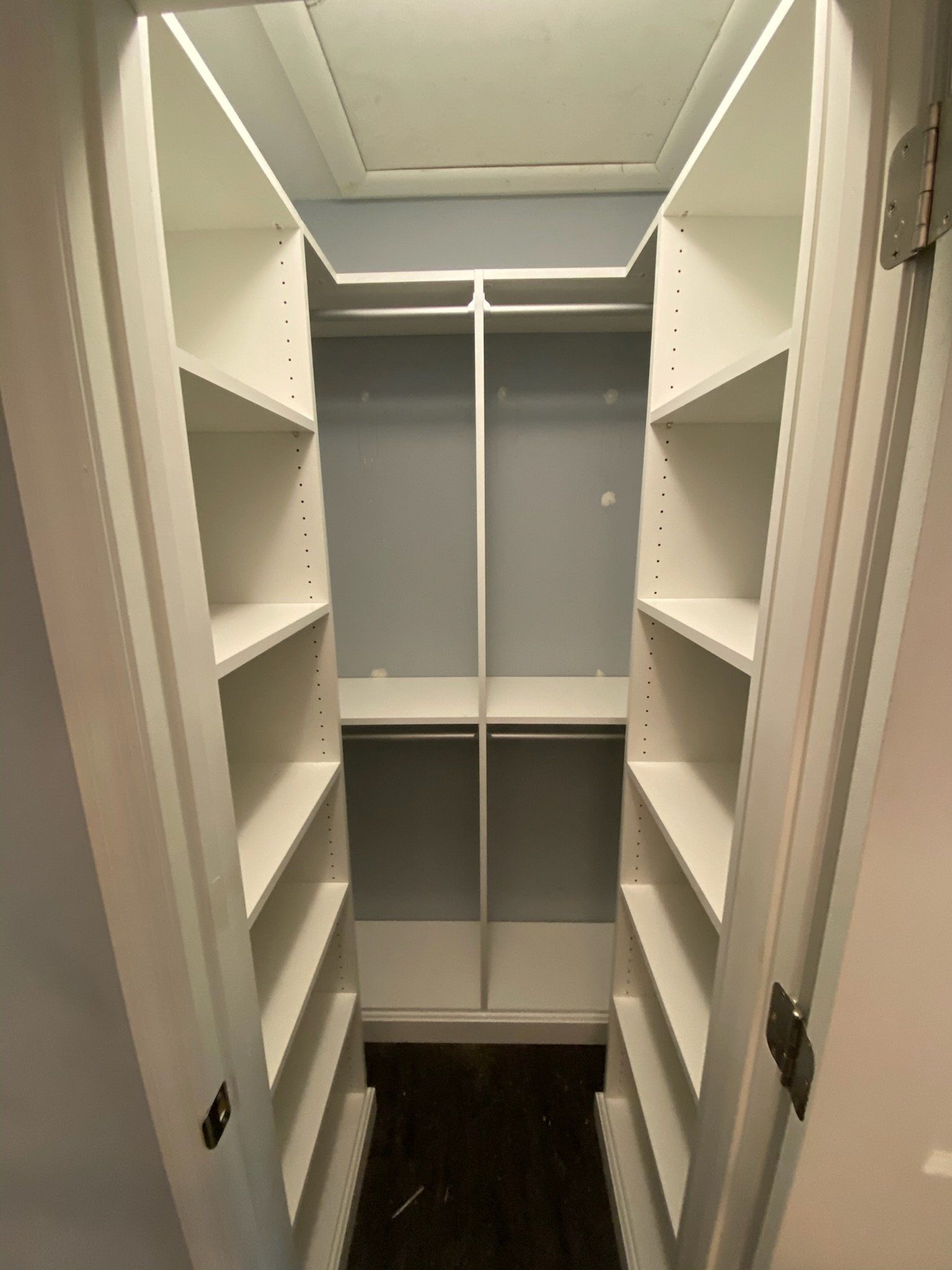a small walk in closet with lots of shelves